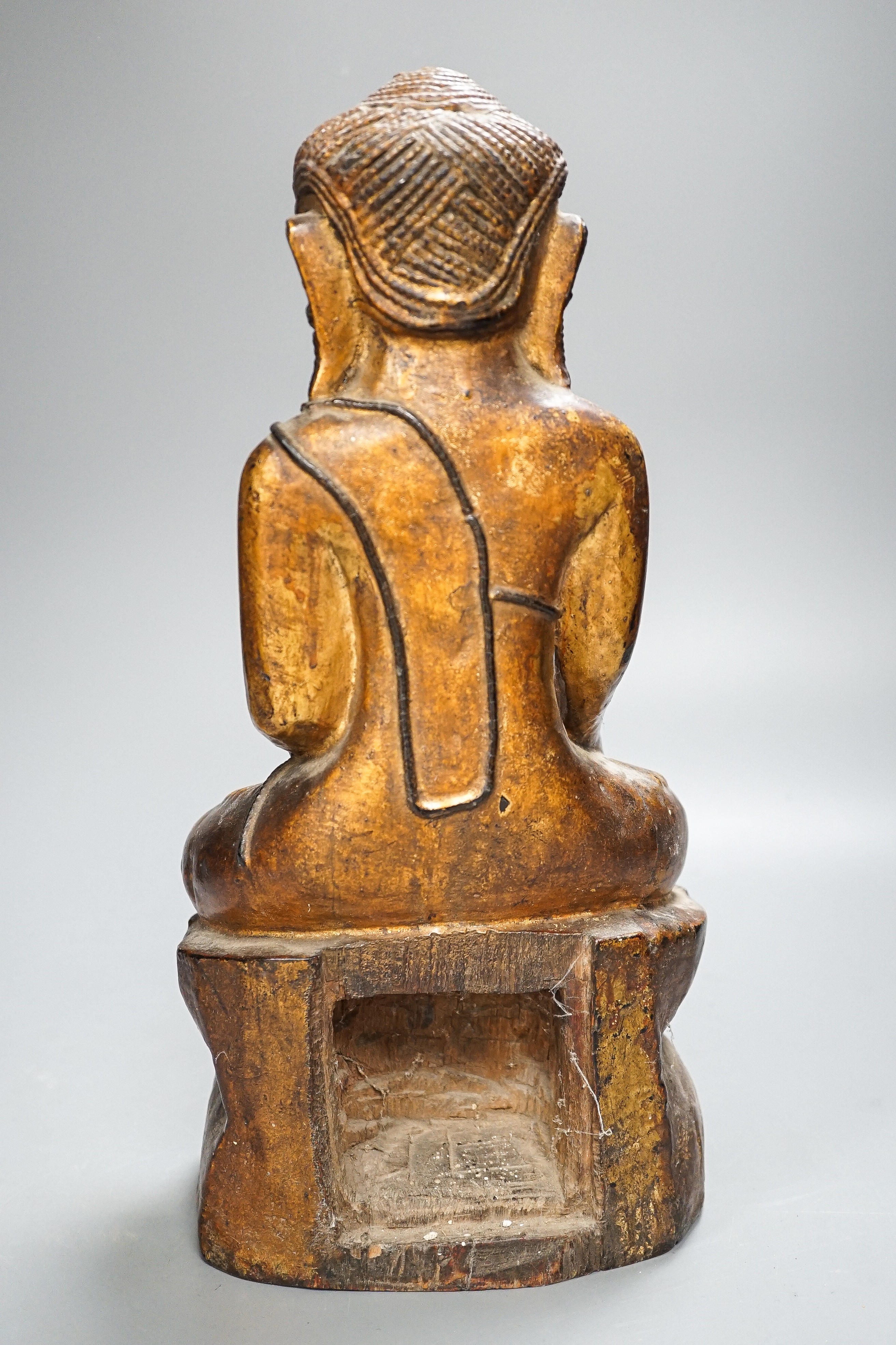 A Burmese gilded carved wooden figure of Buddha, 35 cms high.